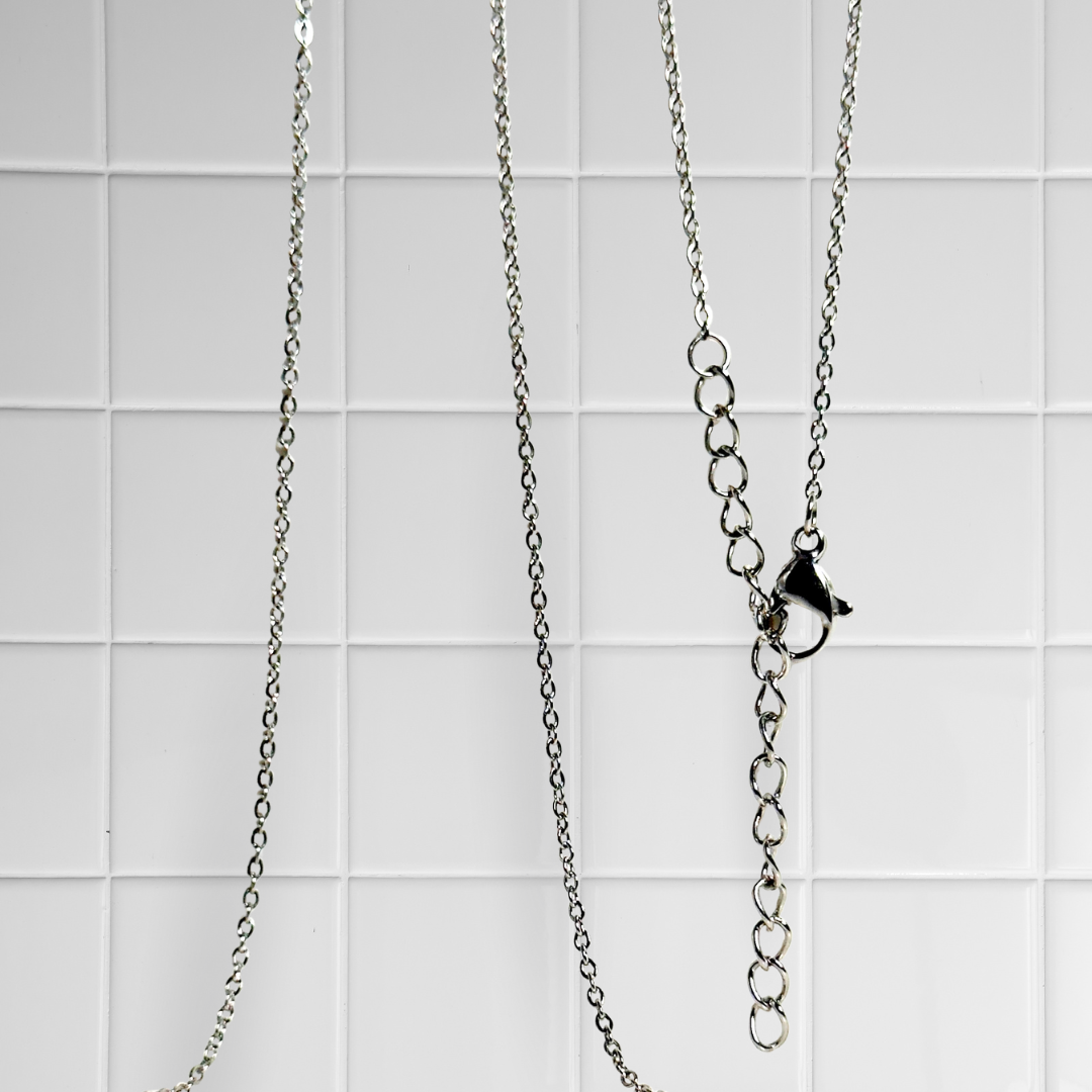 Silberne Link Chain Kette vor weißem Kachel-Hintergrund