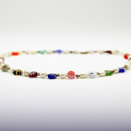 Bunter Perlen-Choker mit verschiedenen Suesswasserperlen und goldenen Details auf weißem Hintergrund