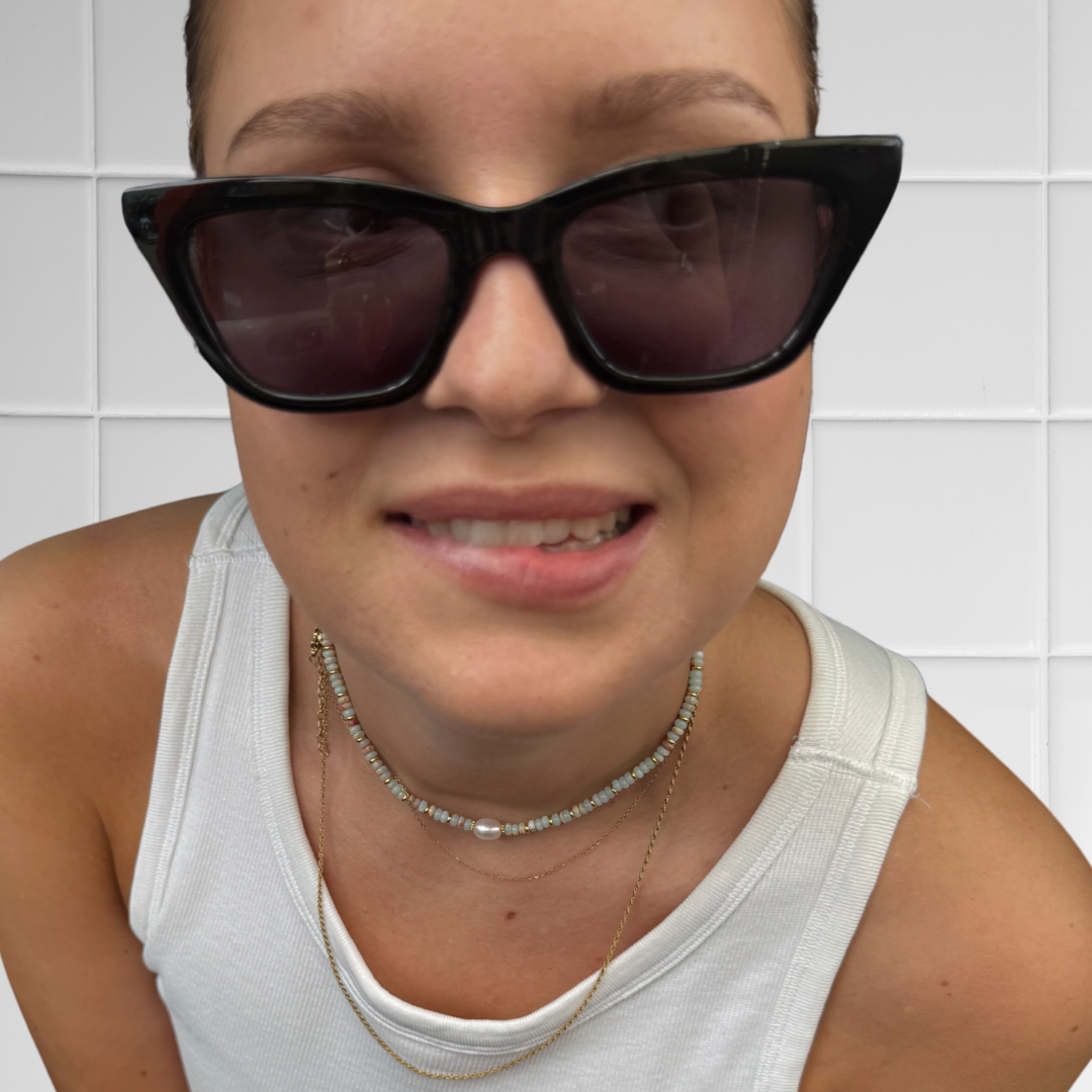 Frau trägt hellblau-rostfarbenen Perlen-Choker mit großer Perle, Nahaufnahme des Halsbereichs