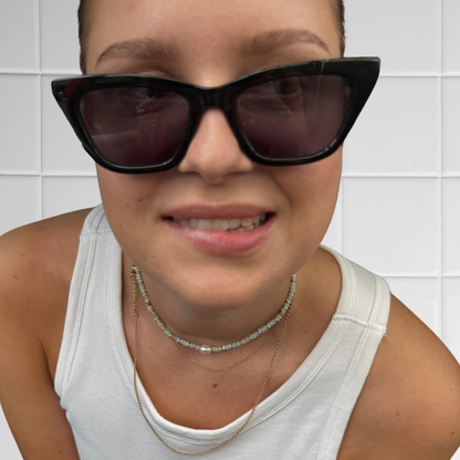 Frau trägt hellblau-rostfarbenen Perlen-Choker mit großer Perle, Nahaufnahme des Halsbereichs