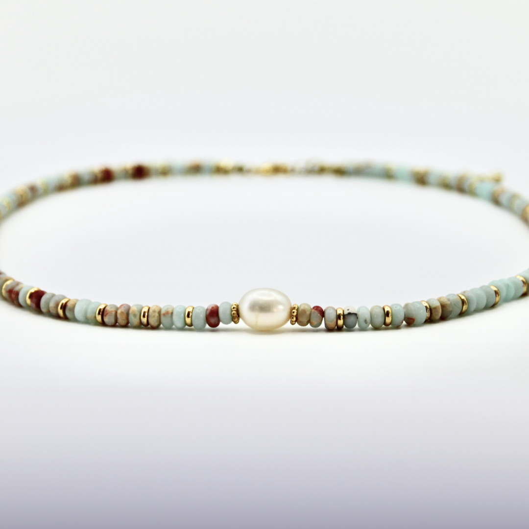 Hellblau-rostfarbener Perlen-Choker mit goldenen Details und einer großen Perle auf weißem Hintergrund