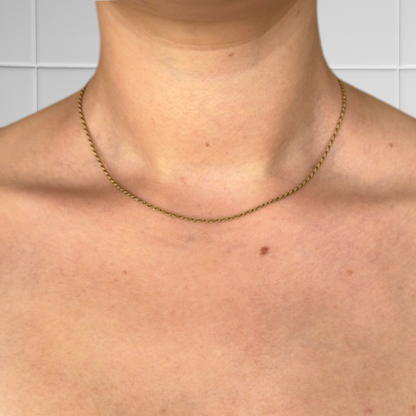 Kurze goldene Rope-Kette getragen, Nahaufnahme des Hals- und Brustbereichs vor hellem Hintergrund