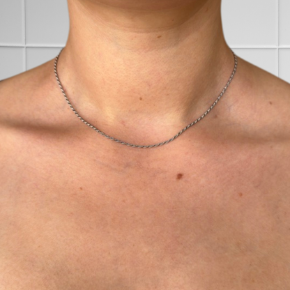 Kurze silberne Rope-Kette getragen, Nahaufnahme des Hals- und Brustbereichs vor hellem Hintergrund