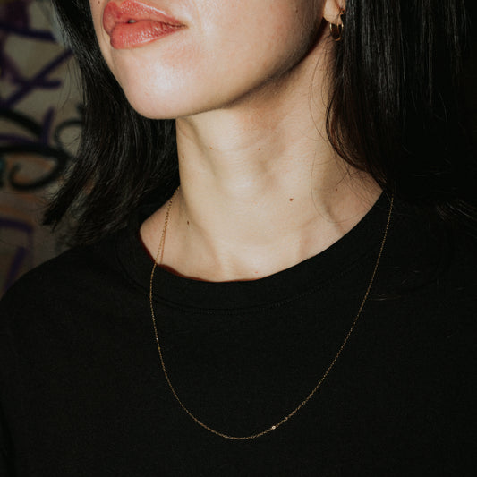 Unisex Goldkette „Lowkey Shy“ lang aus vergoldetem Edelstahl, feine minimalistische Halskette getragen im Close-up.